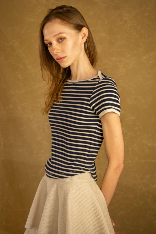 Woman wearing a striped shirt and skirt against a brown background